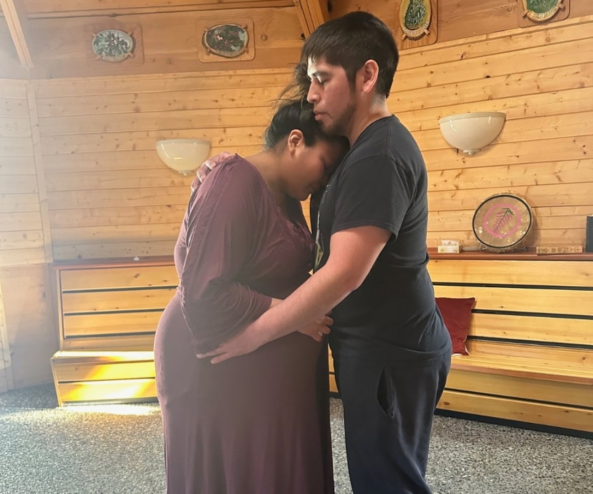A man embraces a pregnant woman.