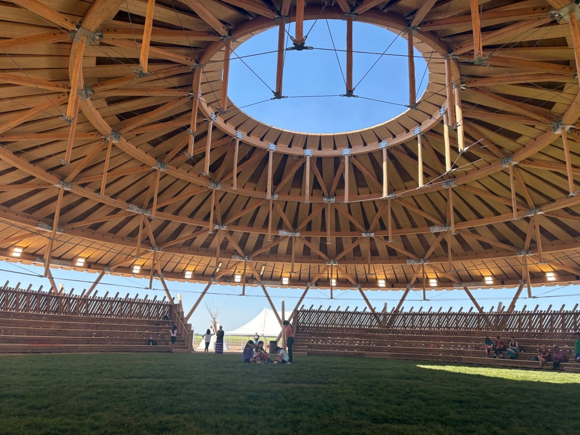Kids play on fresh grass under a wooden arbour.